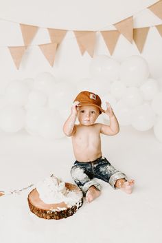 a young boy sitting on the ground with his hands up to his head and cake in front of him