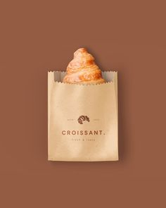 a croissant wrapped in brown paper on top of a brown background with the word crossant