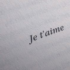 the word je t'aime is written in black ink on a white paper