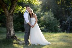 a bride and groom standing in front of a tree