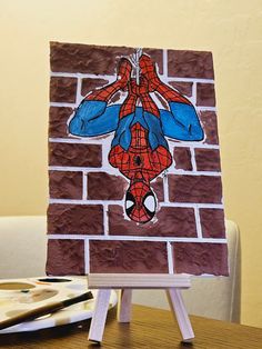 a drawing of a spider - man on a brick wall is displayed in front of a small easel