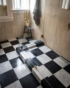 a black and white checkered floor in a bathroom with glass shower door, towel rack, and window