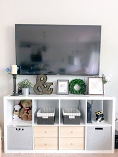 a white entertainment center with baskets and stuffed animals