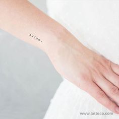 a woman's arm with a small tattoo on it that says alive in cursive writing