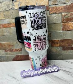 a travel mug with words on it sitting next to a brick wall