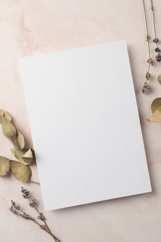 an empty sheet of paper next to some dried flowers