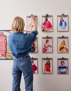 a woman standing in front of a wall with pictures hanging on it's sides