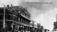 an old black and white photo of people walking down the street in front of buildings