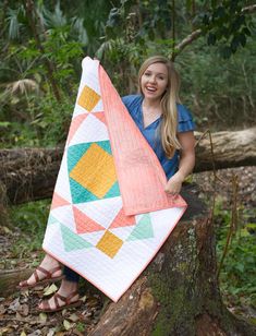 a woman sitting on a tree stump holding a quilt