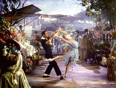 a man and woman dancing in front of flowers