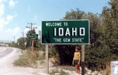 a man standing in front of a road sign