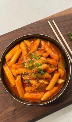 a bowl filled with food next to chopsticks on top of a wooden table