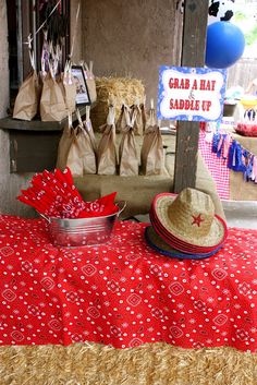 a table topped with bags and hats next to a sign that says grab a hat saddle up