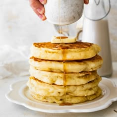 a stack of pancakes being drizzled with syrup