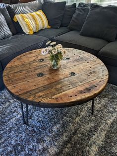 a wooden table sitting on top of a blue rug in front of a gray couch