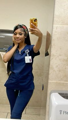 a woman in scrubs taking a selfie in the bathroom mirror with her cell phone