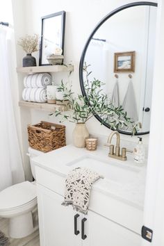 a white bathroom with a round mirror above the sink