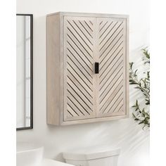 a wooden cabinet mounted to the side of a wall next to a toilet and mirror