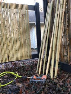 a pile of bamboo sticks sitting next to a window in front of a fenced yard