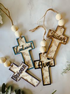 three wooden crosses with the words jesus and an olive branch hanging from them on a marble surface