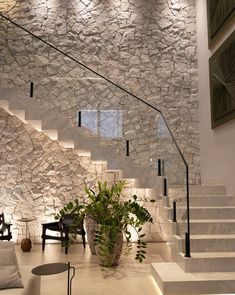 a living room filled with furniture next to a stone wall covered in white walls and stairs