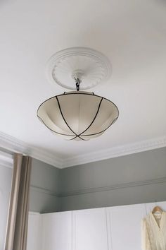 a light fixture hanging from the ceiling in a room with white walls and gray curtains