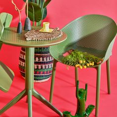 two green chairs sitting next to a table with flowers on it and a potted plant