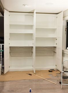 an empty room with white shelving and tools on the floor in front of it