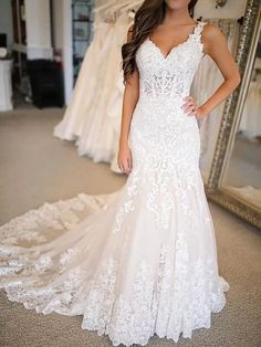 a woman standing in front of a mirror wearing a wedding dress with white lace on it