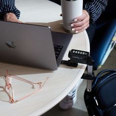 two people are sitting at a table with their laptops and coffee cups in front of them