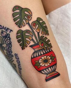 a close up of a person's leg with tattoos on it and plants in a vase