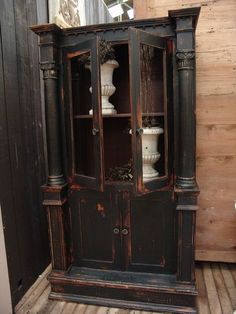 an old wooden cabinet with glass doors on the front and bottom, sitting in a room