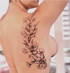 a woman's back tattoo with flowers on her left shoulder and the upper part of her right arm