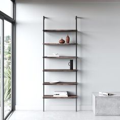 a white room with shelves and vases on the wall next to a large window