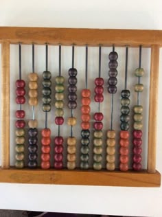 an abacusk with many beads in it on a wooden shelf next to a white wall