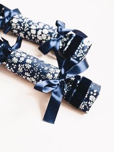 two rolls of blue ribbon with white flowers on them, tied together and sitting next to each other