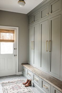 an empty room with gray cabinets and shoes on the floor next to a white door