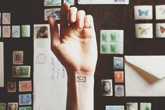 a person's arm with a small tattoo on it and many stamps all over the wall