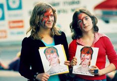 two women with their faces painted in the colors of david beck and paul beck are holding up pictures