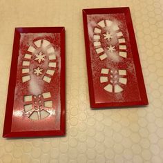 two red plates sitting on top of a table covered in snowflakes and cut outs