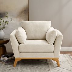 a white chair sitting on top of a rug next to a vase filled with flowers