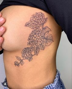 a close up of a person's stomach with flowers tattooed on the side and behind her