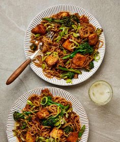 two plates with noodles, broccoli and tofu on them next to a glass of beer