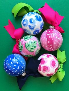 several ornaments with bows are on a green surface and one is pink, blue, and white