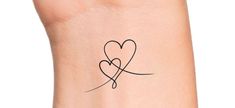 a small tattoo with two hearts on the side of her arm, and an arrow in the middle