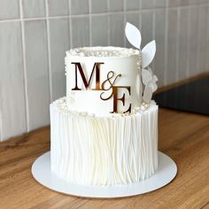 a wedding cake with the letter m and f on it sitting on a wooden table