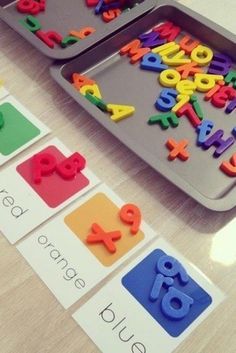 two trays filled with letters and numbers on top of a table next to each other