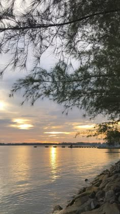 the sun is setting over the water and boats are in the distance