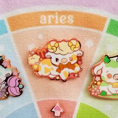 three pin badges with animals on them sitting in front of a color wheel and the words aries