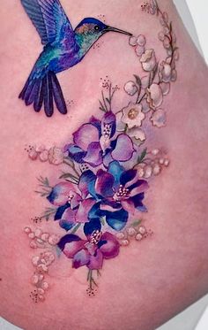 a woman's stomach with flowers and a hummingbird on it